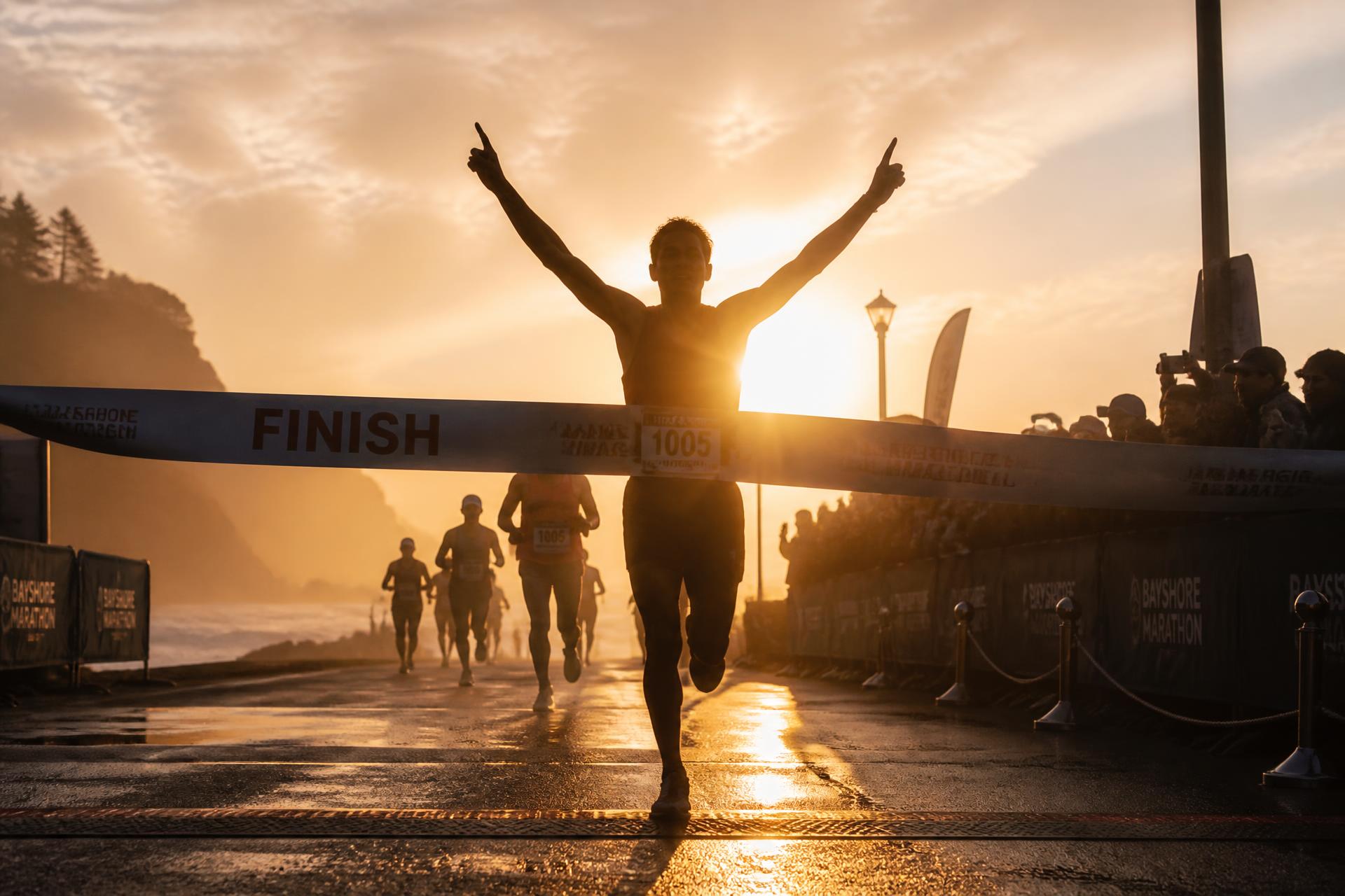 Runner crossing a marathon finish line at sunrise